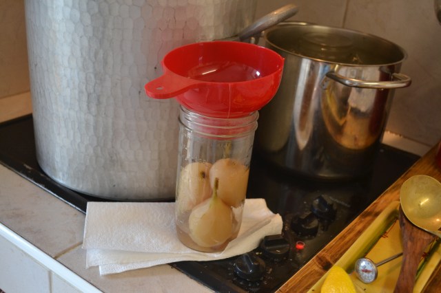 Step 6: Using a funnel to keep the rims clean, add whole pears to jars.